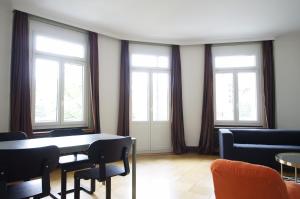 a room with a table and chairs and windows at ReLiving - Historic City Apartment in Luzern