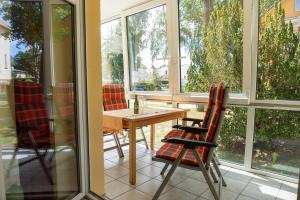 een afgeschermde veranda met een tafel en stoelen bij Ostseepark Waterfront-Karavelle in Heringsdorf