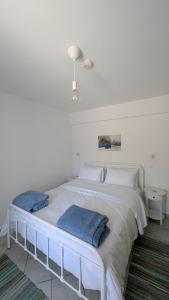 a white bed with two blue pillows on it at Thama Poros-Nostos in Poros +9 photos