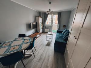 a living room with a table and a blue couch at Apartament Keja Olecko in Olecko