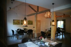 une salle à manger avec des tables, des chaises et des lustres dans l'établissement Pļavas, à Ainaži