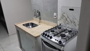 a kitchen with a stove and a sink at Apartamento Garden CLIMATIZADO in Muriaé