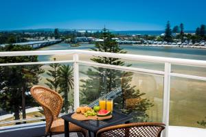 a table with a plate of fruit on a balcony at Oaks The Entrance Waterfront Suites in The Entrance