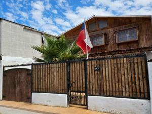 a house with a flag in front of a gate at Hostal Sol y Luna - a 10 min del aeropuerto & Desayuno Incluido in Santiago