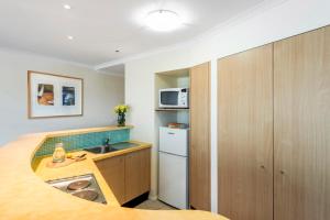 a small kitchen with a sink and a microwave at Oaks The Entrance Waterfront Suites in The Entrance
