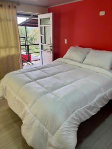 a large white bed in a bedroom with a red wall at Hotel Santafe P&P in Estación El Salto