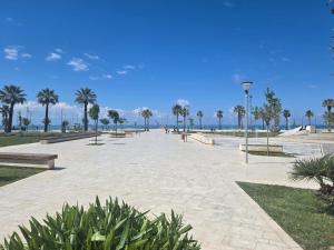 a park with benches and palm trees on the beach at Sea view Captain Apartment Durres in Durrës