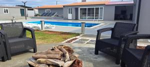 a patio with two chairs and a fire pit and a pool at 3BL Retreat - Escape & Poolparty in Praia da Vitória +8 photos