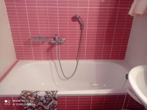 eine Badewanne mit Dusche in einem rosa gefliesten Badezimmer in der Unterkunft Κατοικία στην Κουτσουπιά in Kókkinon Nerón + 8 Fotos