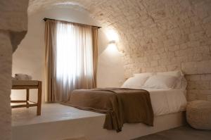a white bedroom with a bed and a window at Palazzo Marconi in Locorotondo