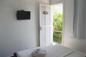 a white room with a bed with a window at Peixe Crew Centro in Búzios
