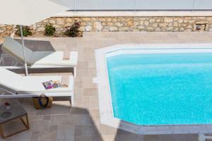 GállosにあるDeluxe Villa Ianthos - Outdoor Hot Tub & Kids Poolの椅子とパラソルの隣にスイミングプールがあります。