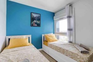 - 2 lits dans une chambre avec un mur bleu dans l'établissement Large - Paris, DisneyLand, Villepinte Expo, CDG, à Sevran