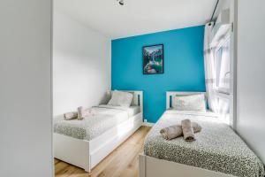 - 2 lits dans une chambre avec un mur bleu dans l'établissement Large - Paris, DisneyLand, Villepinte Expo, CDG, à Sevran