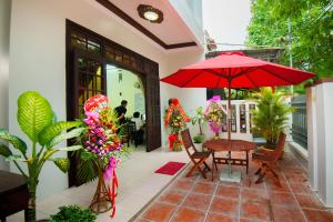 un patio con una mesa y una sombrilla roja en Royal Homestay, en Hoi An