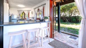 a kitchen with a counter and two stools at a bar at Sea Breeze Apartment in Wilderness