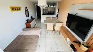 a living room with a large television and a table at Excelente Flat mobiliado de 54M2 in São Luís