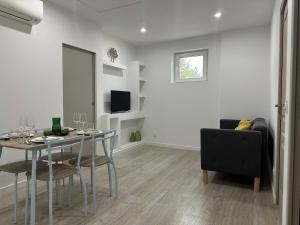 a white living room with a table and a chair at Appartement cosy parking privé in Tarbes