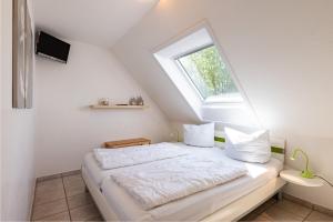 a white bedroom with a bed with a window at Ankerlicht in Norddeich