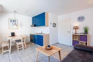 a kitchen and living room with blue cabinets and a table at Ankerlicht in Norddeich