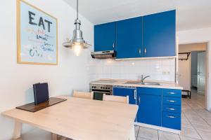 a kitchen with blue cabinets and a wooden table at Ankerlicht in Norddeich +7 photos