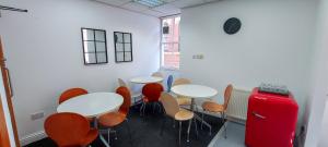a room with tables and chairs and a red suitcase at R S Hostels - Leeds in Leeds
