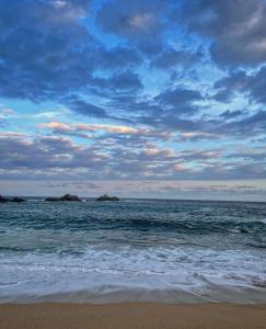 a beach with a cloudy sky and the ocean at Casa Andivi, Placer sin fin in San Pedro Pochutla