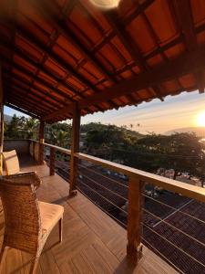 a balcony with chairs and a view of the sunset at Casa amarela in Cambaquara +47 photos