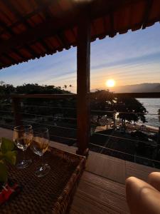 a table with glasses of wine on a balcony with the sunset at Casa amarela in Cambaquara