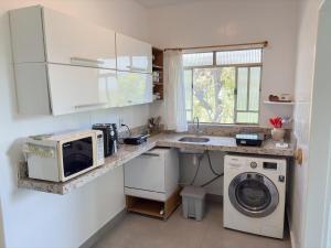 a kitchen with a washing machine and a microwave at Casa de campo in Itaúna