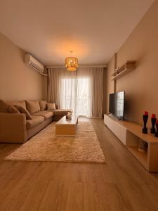 a living room with a couch and a tv at Comfy Hotel Apartament in Madinaty