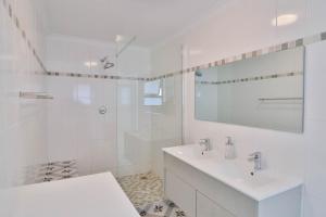 a white bathroom with a sink and a shower at Thalassa in Bettyʼs Bay