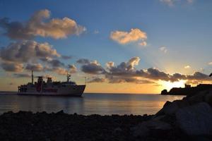 a ferry boat in the ocean with a sunset at Appartamento il Palazzone in Capraia +7 photos