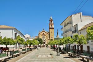 a street with benches in front of a church at Casa Paco & Carmela in Algodonales