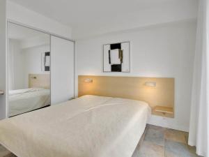 ein weißes Schlafzimmer mit einem Bett und einem Spiegel in der Unterkunft 6 person holiday home on a holiday park in Rømø in Sønderby + 52 Fotos