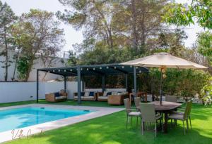 Un patio con mesa y sombrilla junto a una piscina. en Villa cala tarida, en Cala Tarida