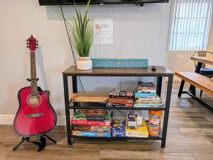 una chitarra rossa appoggiata accanto a un tavolo con dei libri di Ranch Style, King Bed, Guitar, BBQ- 1 Dollar rides to Beach & Downtown a Lake Worth