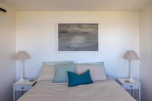 une chambre avec un lit avec des oreillers bleus dans l'établissement Woodside Bay Cottage, Woodside Bay - Be My Guest Waiheke, à Waiheke Island