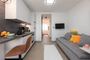 Una cocina y una sala de estar con un sofá gris en una habitación. en Apartments by the sea Baska, Krk - 24433, en Baška