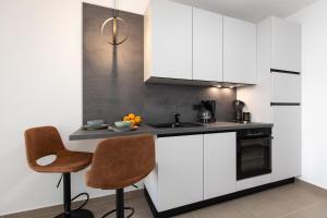 una cocina con armarios blancos y una encimera con 2 sillas en Apartments by the sea Baska, Krk - 24433, en Baška