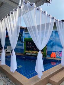 a pool with white curtains and a fish tank at Pool Smile Villa in Bangsaen