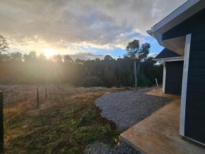 a house with the sun setting over a field at Casa Parcela, Bosques de Frutillar in Frutillar