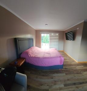 a bedroom with a bed and a couch and a window at Casa Parcela, Bosques de Frutillar in Frutillar +4 photos