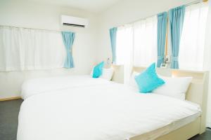 two beds in a bedroom with blue curtains at 貸切戸建て3beds Private House Sleep Man in Kagoshima