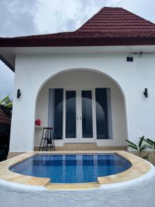 a villa with a swimming pool in front of a house at Lake Side Retreat & hot spring in Kubupenlokan