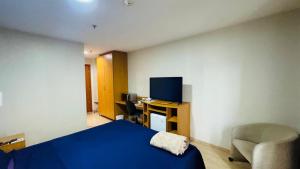 a bedroom with a blue bed and a chair and a desk at Flat aconchegante in Brasilia