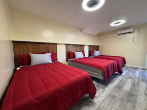 zwei Betten in einem Zimmer mit roten Decken in der Unterkunft Apache Motel in Ruidoso