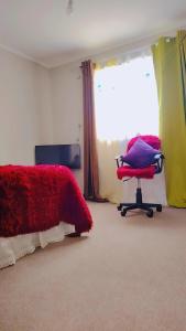 a bedroom with a bed and a chair and a window at Casa TREKKING TOUR ESTANCIA EL SAUCE COQUIMBO in Coquimbo