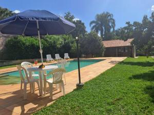 a table and chairs with an umbrella next to a pool at Chácara Vivenda Aconchego in Itupeva