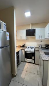 a kitchen with white cabinets and a stove top oven at Departamento frente al Arena Maipú Mendoza in Maipú